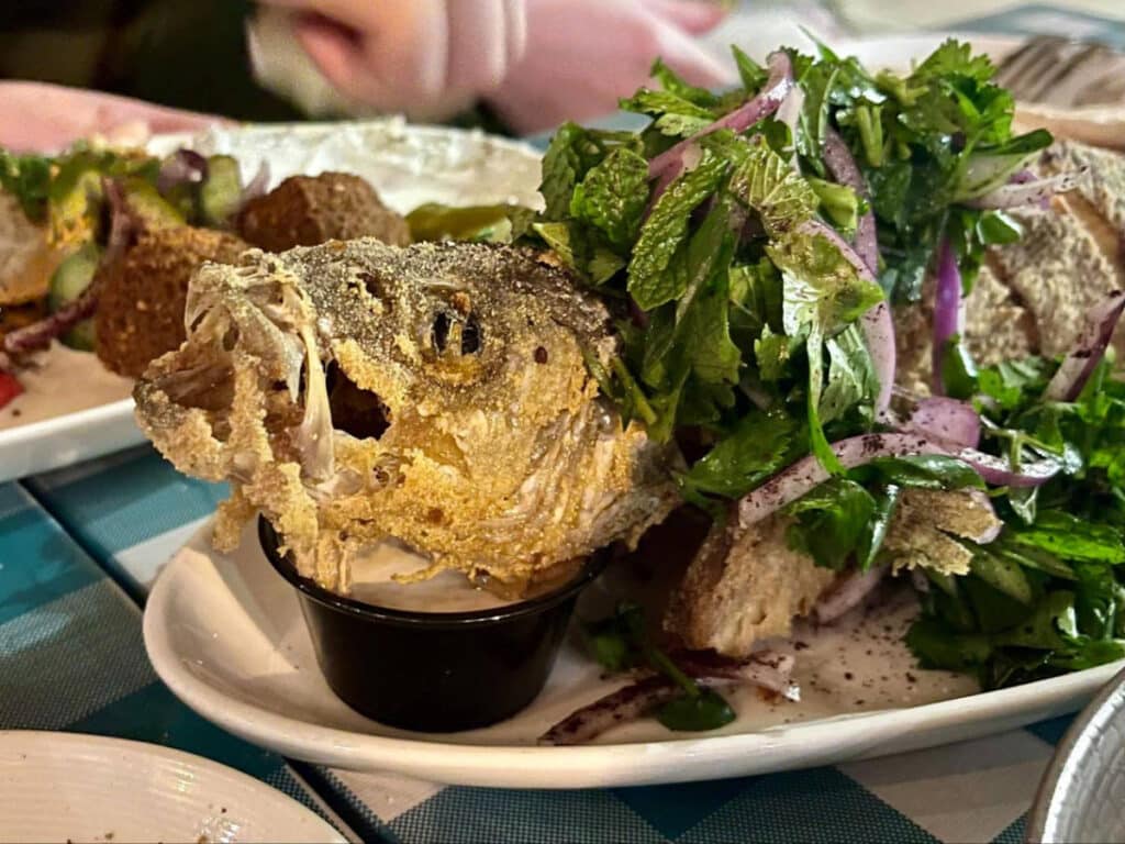 A whole fried branzino on a plate in Beit Rima