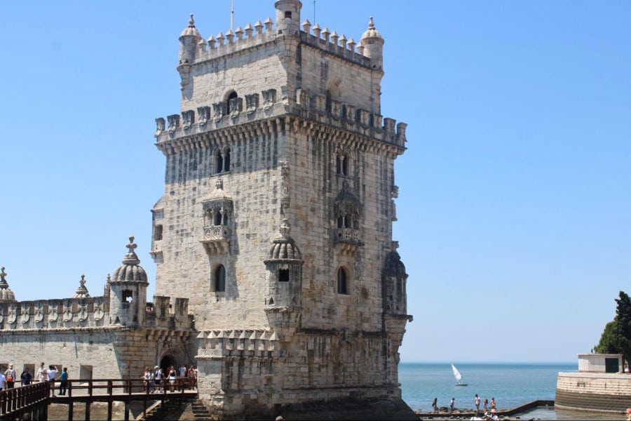 People cross the bridge and enter the Belem Tower near the beach of Lisbon.
