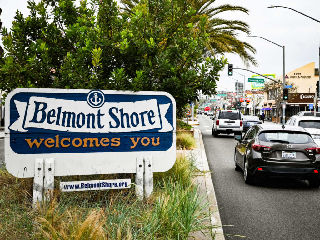The vehicles passing by the welcome signage of Belmont Shore