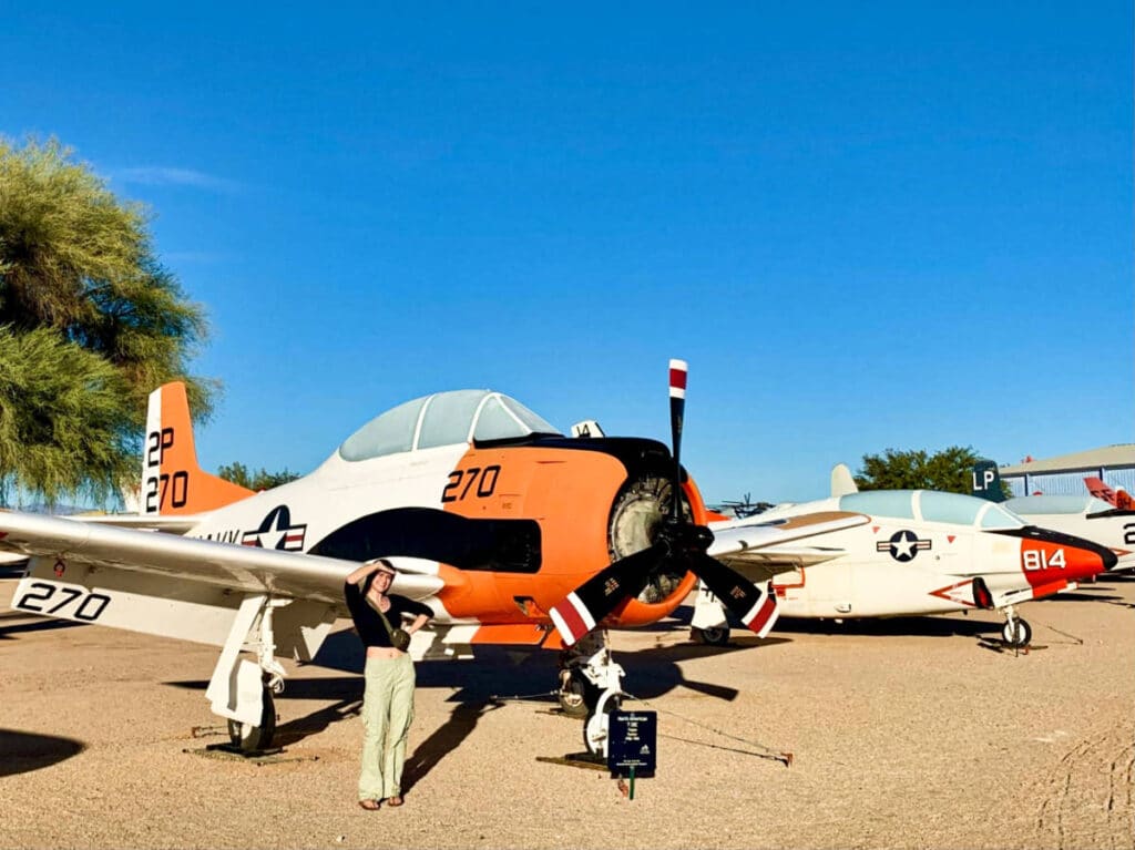 The author Betty Hurd, posing for a photo in front of the old planes at the Pima Air and Space Museum