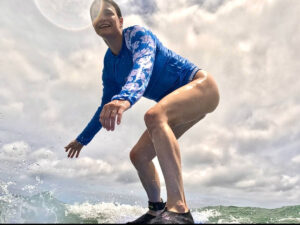 The author Betty Hurd wearing a rash guard while surfing on a sunny day