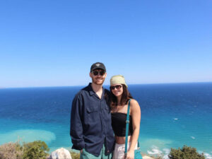 The author Betty Hurd and her partner with an overlooking view of the ocean on a sunny day