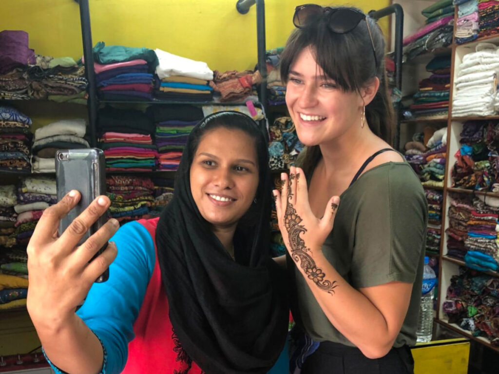 Betty taking a selfie with a local and showing her henna tattoo