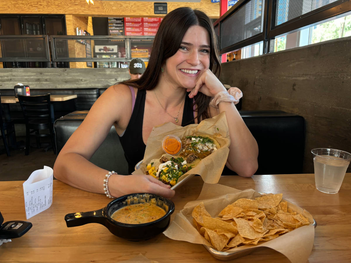Travel Lemming writer Betty Hurd smiling for a photo with her meal at Torchy's Tacos