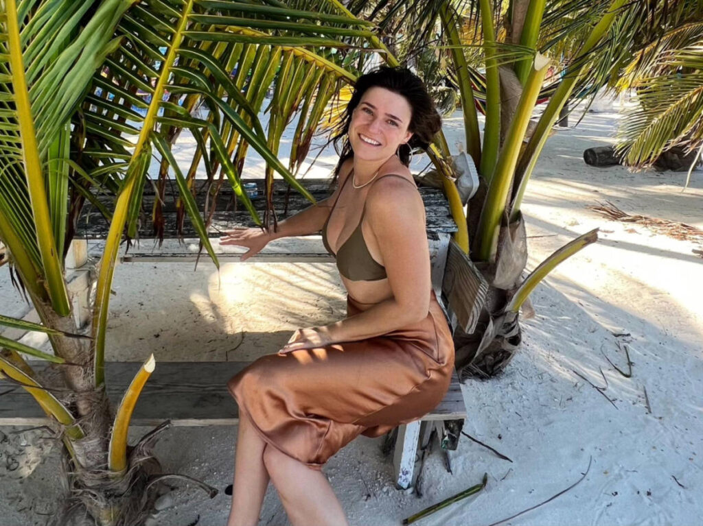 The author Betty Hurd posing for a photo on a bench at the beach