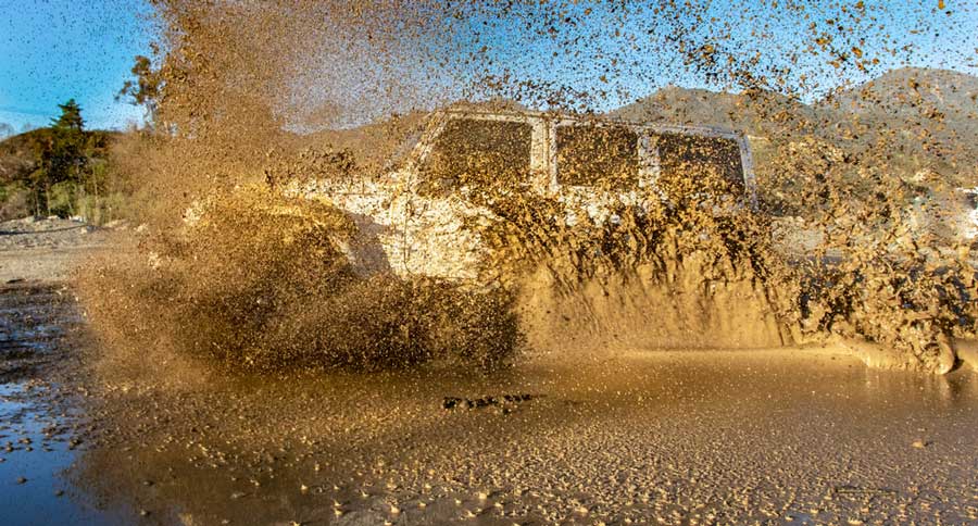 A 4x4 jeep plowing through a mud puddle in Big Bear Jeep Experience