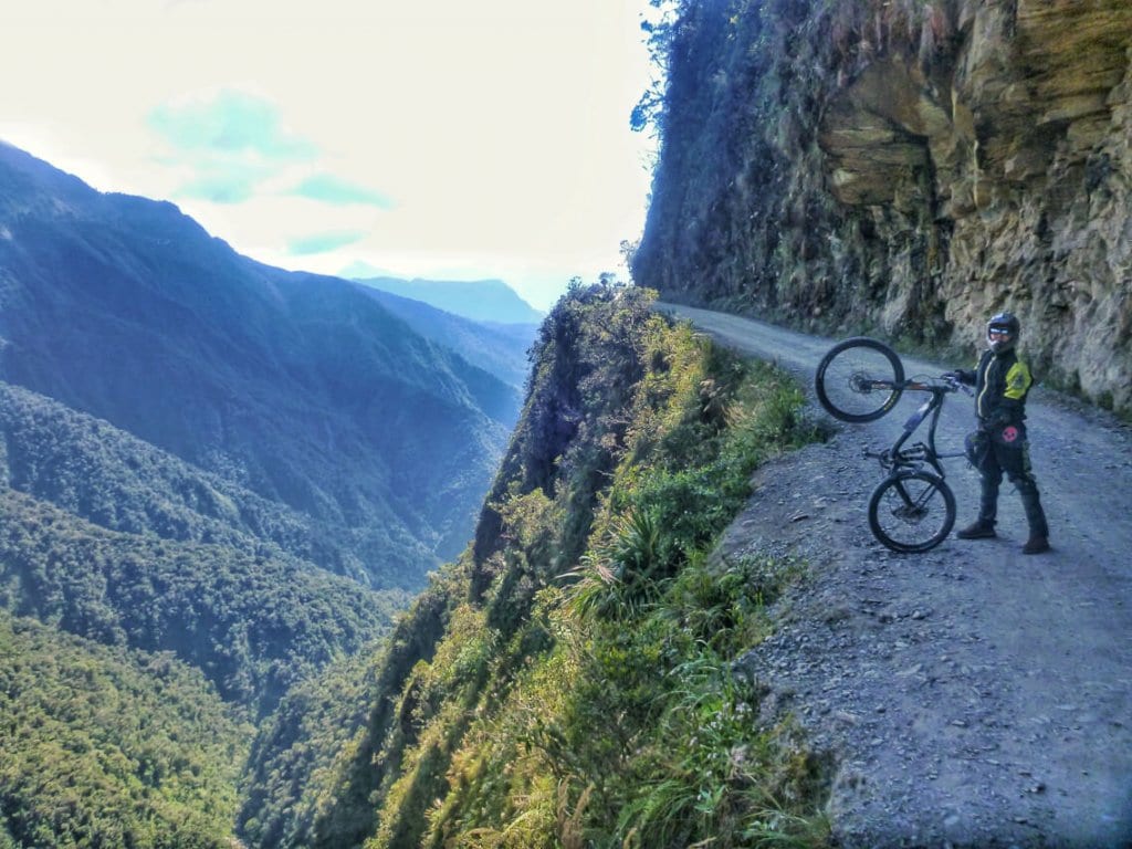 A biker posing for a photo with his bicycle in the Death Road