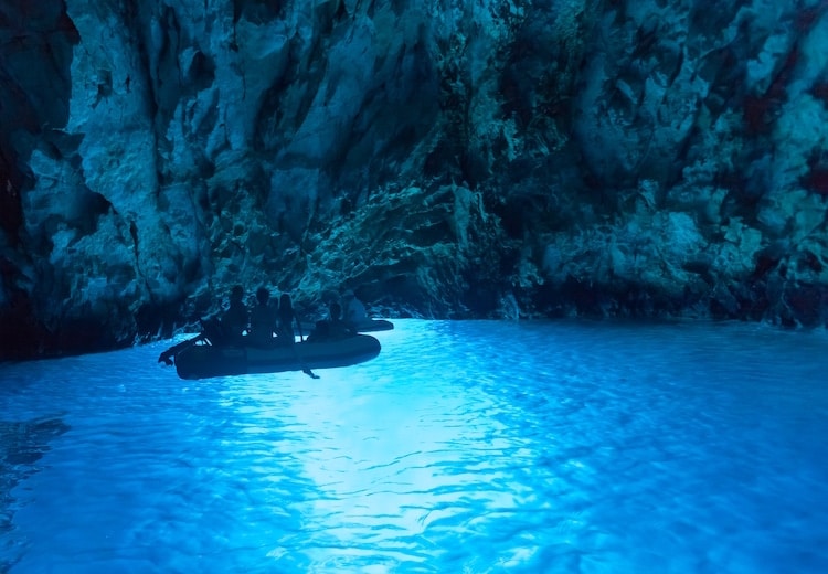 A boat floats in the vibrant blue waters of a cave on Bisevo Island