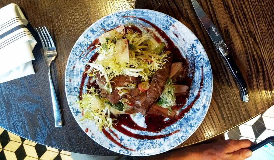 A dish on a plate at Bistro LeRoux with fork and knife on the side