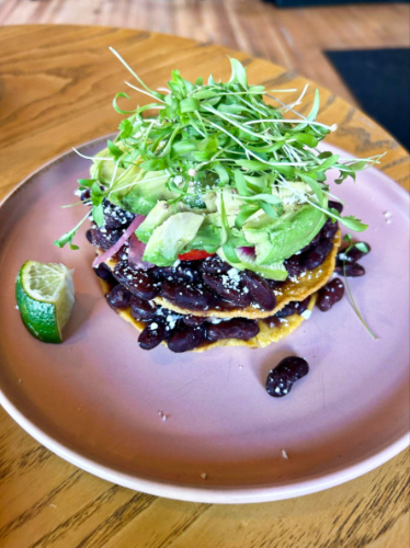 A plate of black bean tostadas topped with greens