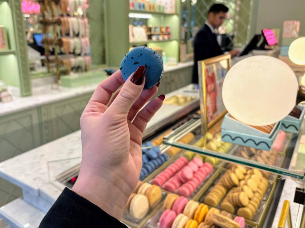 Holding a Blue Marie Antoinette macaron at Ladurée