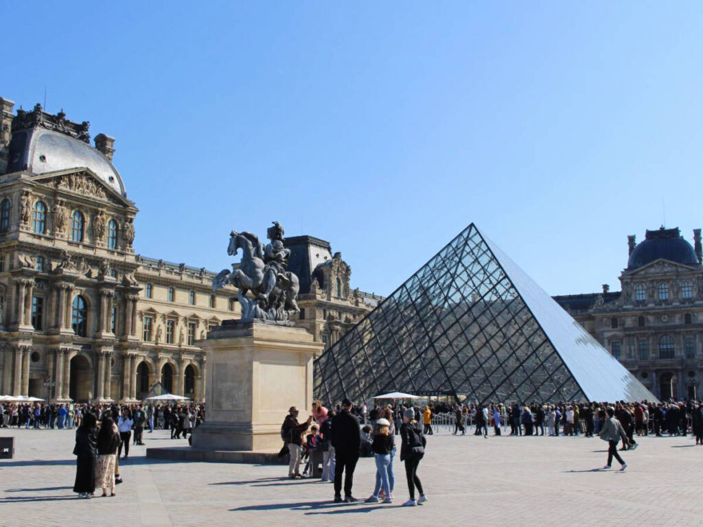 Clear blue sky over the people outside the Louvre Museum
