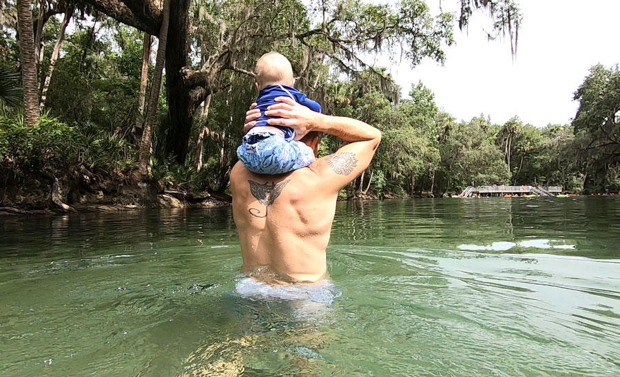 View of a baby on her father's shoulder walking on the shallow part of Blue Spring State Park