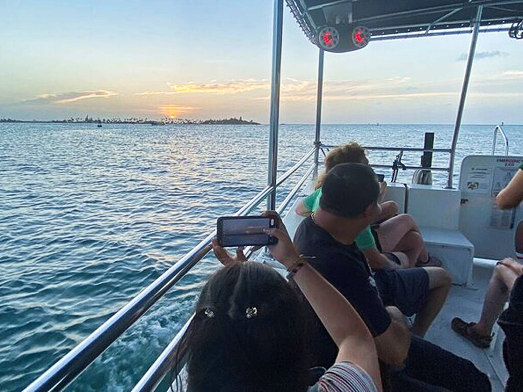 A woman taking a photo of the sunset from the boat tour