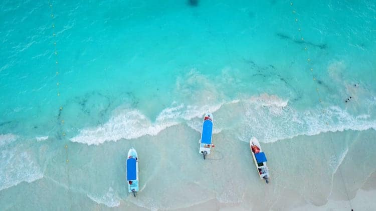 An aerial shot of three boats resting in the water of Tulum