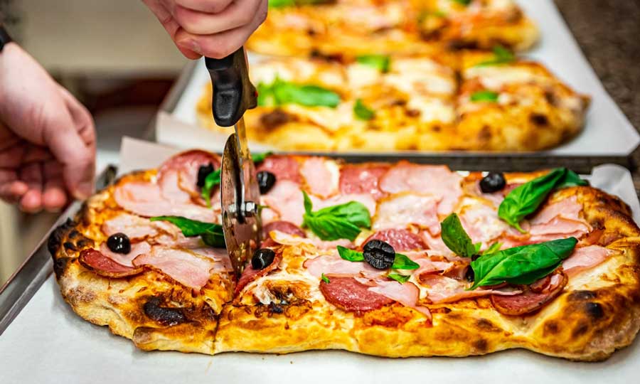 A pizza being a cut in Bonci Pizzeria