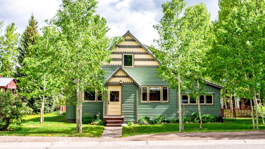 A green summer house with different trees around in Crested Butte
