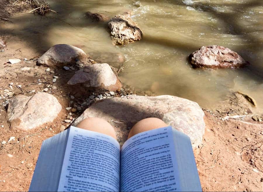 A book on the lap near the river in Zion National Park