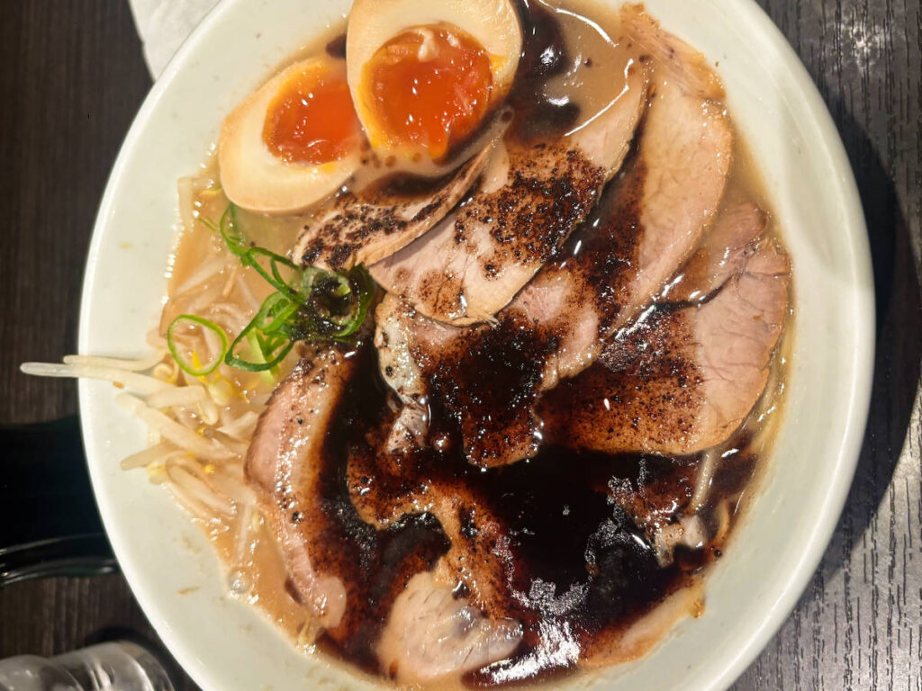 A bowl of ramen topped with meat and sliced eggs