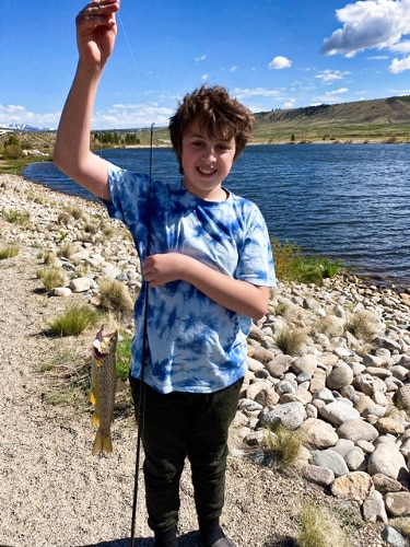 The author's son holding a fishing rod with fish on it