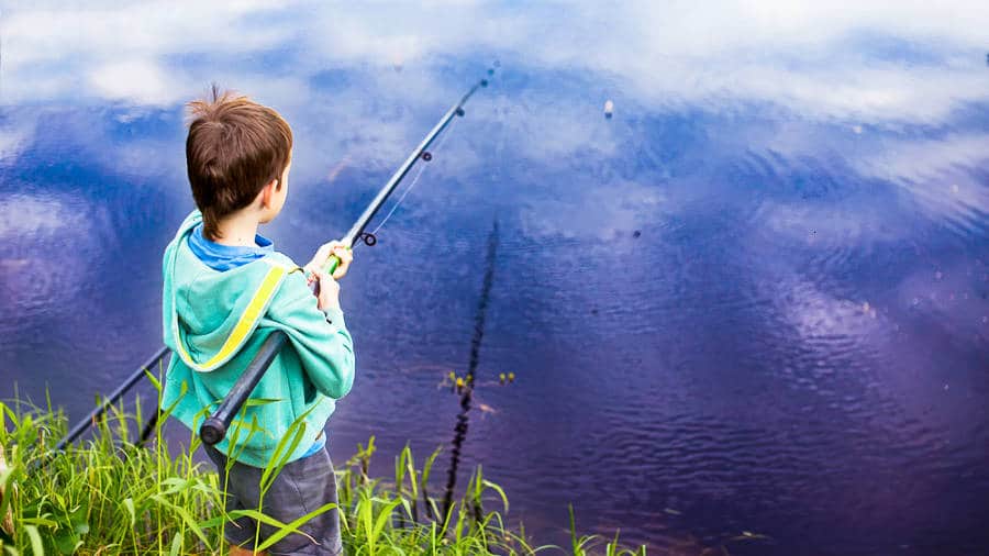 A boy holding a fishing rod near the water
