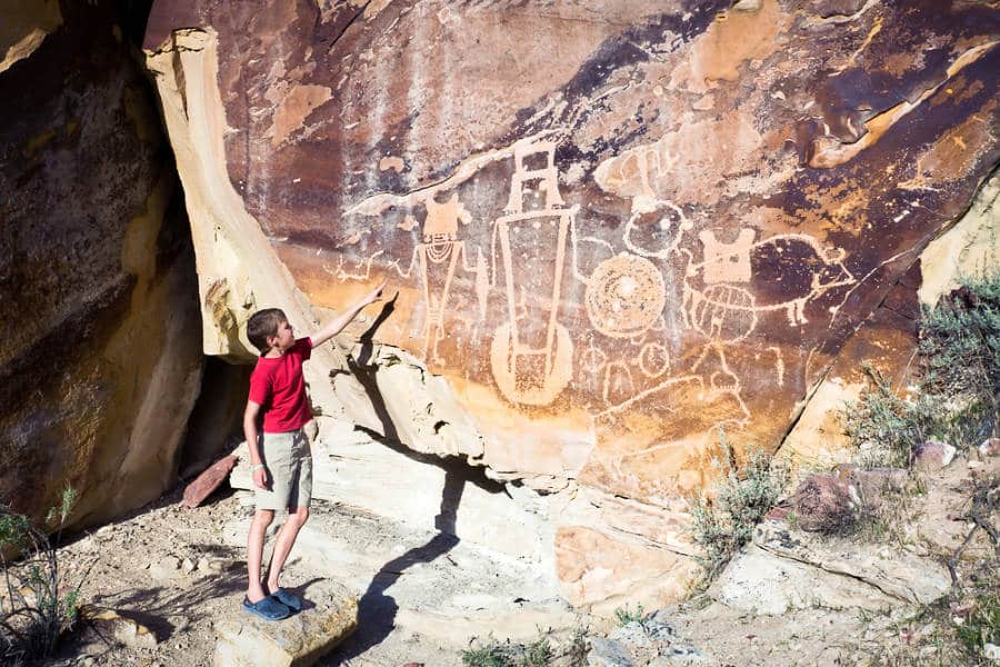 View of a kid pointing on the wall with petroglyphs in Dinosaur National Monument