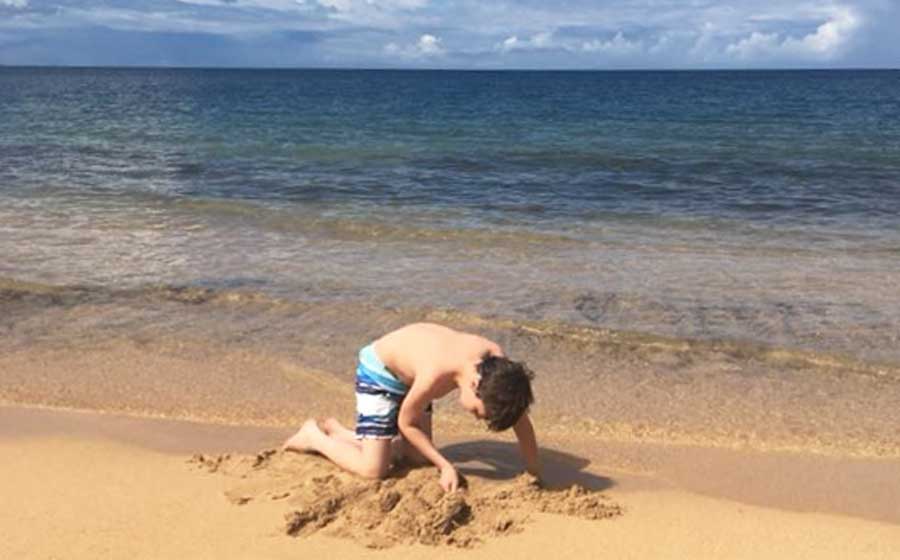 A boy playing on the sand on a beach
