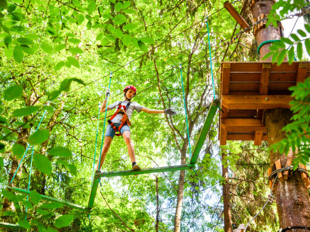 A boy with safety harness doing the rope obstacle course at the treetop adventure park