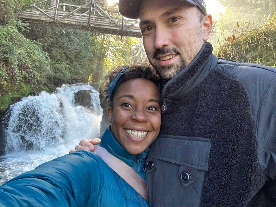 Author Chelsea with her husband taking a selfie with the lower falls in Brewery Park at Tumwater Falls on their background