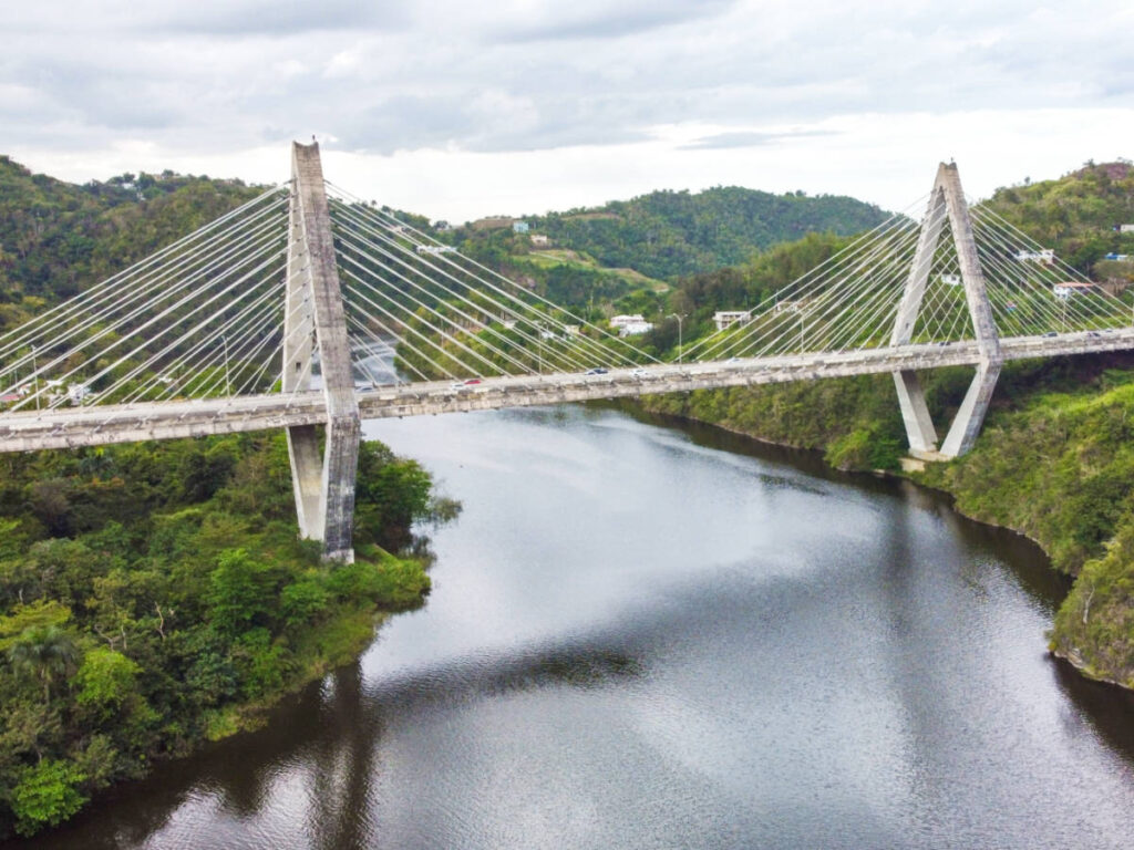 A cable bridge over the La Plata River surrounded by greenery