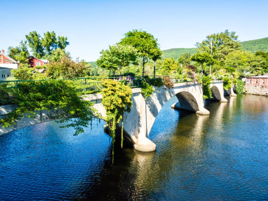 View of the Bridge of Flowers surrounded by greenery in Shelburne Falls on a sunny day
