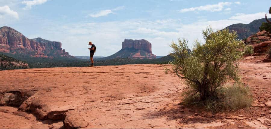 A man standing at the summit with a scenic background 