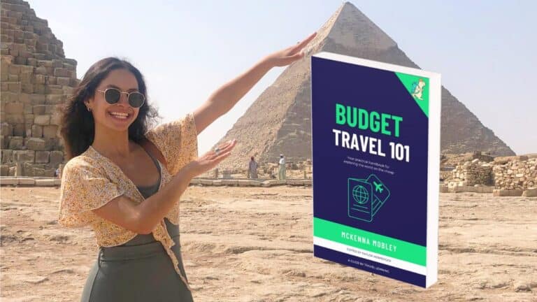 McKenna Mobley pointing to a copy of Budget Travel 101, in front of pyramids in Egyp