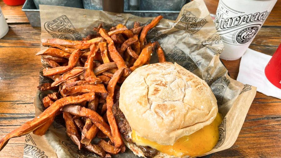 A huge burger with melting cheese inside and fries on the side