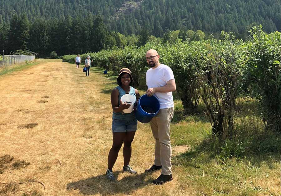 The author with her husband holding a bucket with the blueberries that they picked