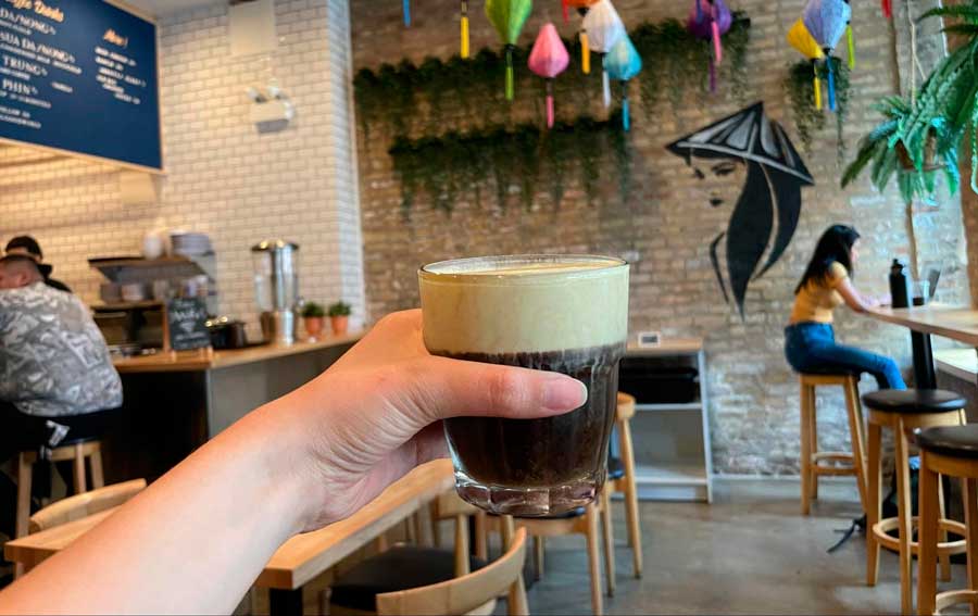 The author holding her glass of iced vanilla egg custard coffee from Cà Phê Dá