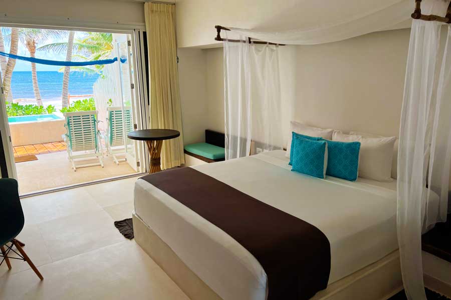 A bed on a room with a beach view in Cabañas Tulum Hotel