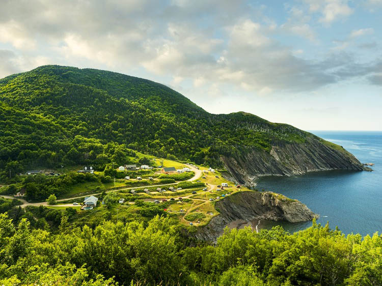 Mountain on coastal area with curvy road and few houses on Cabot Trail