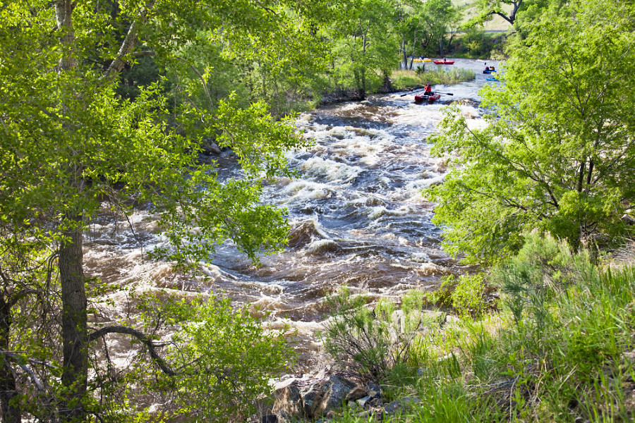 View of the rapid whitewater of Cache la Poudre River and the rafters in the distance