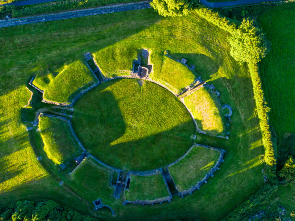 Aerial view of the Roman Amphitheatre covered and surrounded by greenery in Caerleon