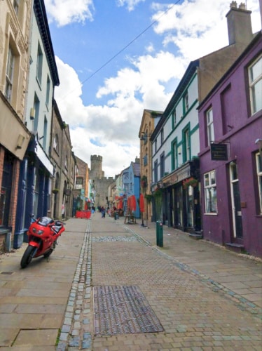 A red motorbike parked outside buildings of Caernarfon