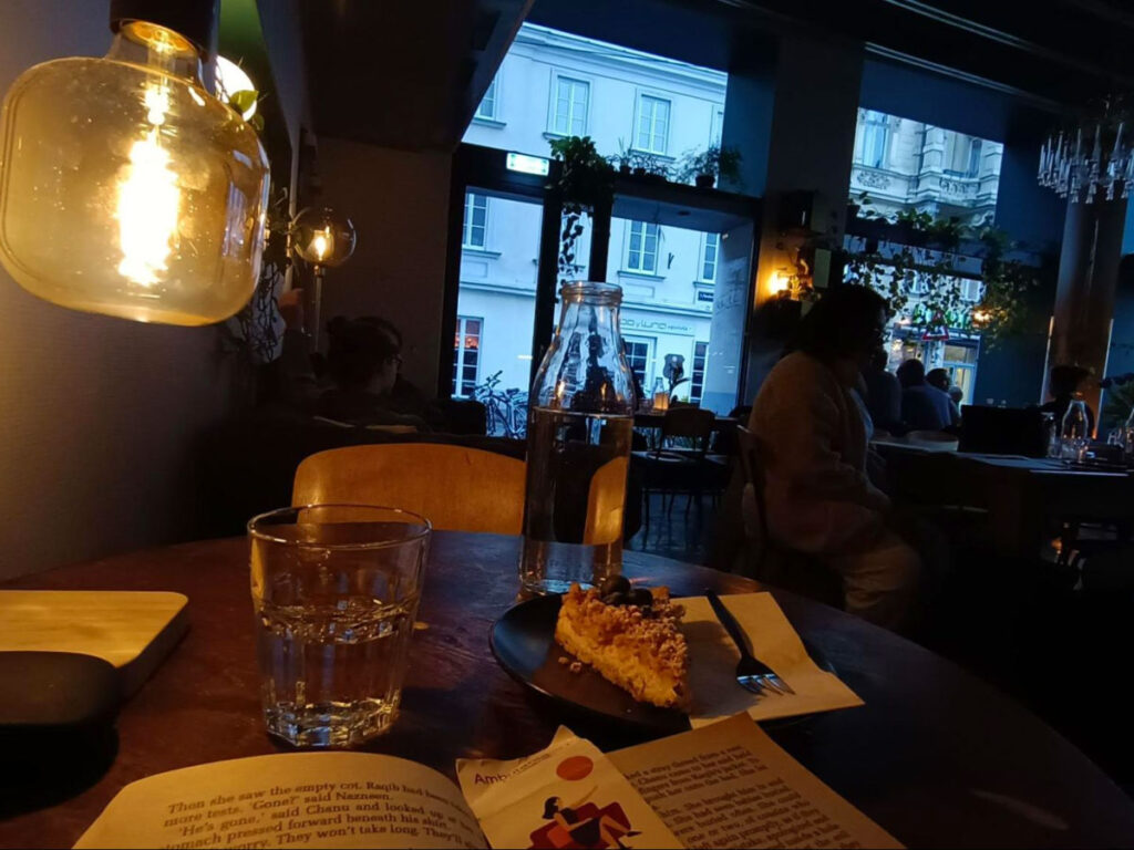 A table at Café 7stern in Vienna with a book, cake and a glass of water