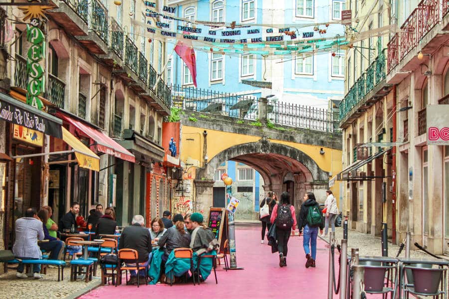 People strolling and eating at the vibrant and colorful pink street of Cais do Sodré in Lisbon