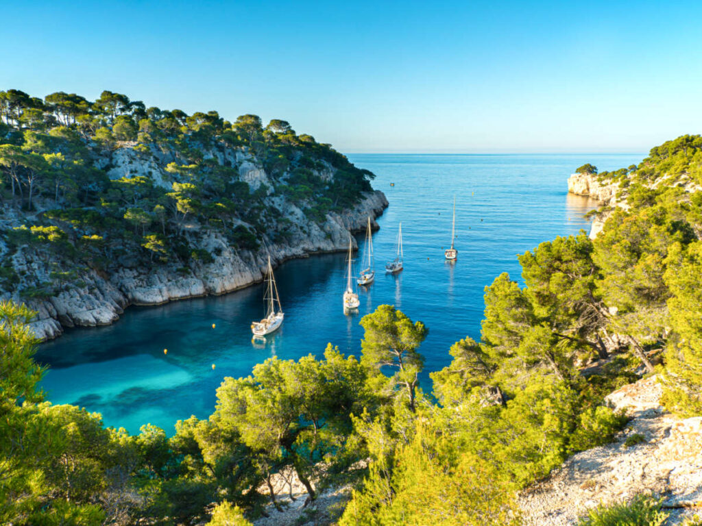 Aerial view of the boats sailing on Calanque de Port Pin Beach, seen from the lush mountains