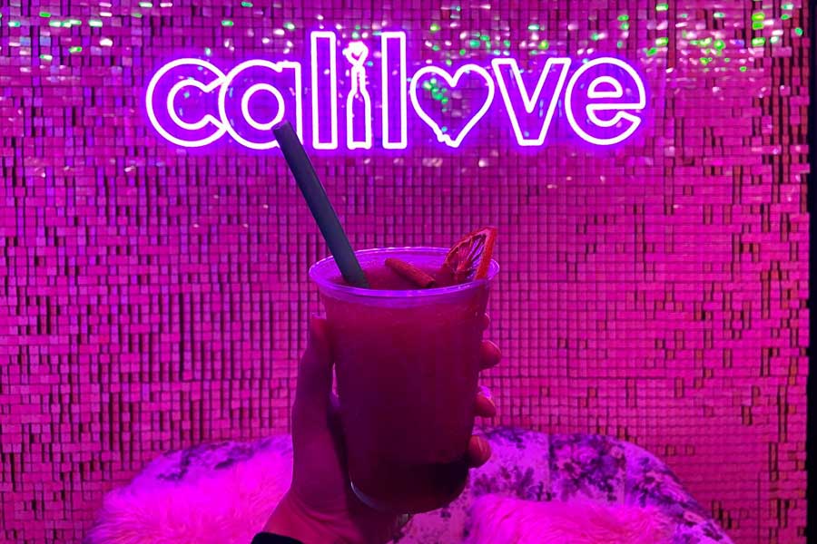 The author holding a sangria slushie and the illuminated sign of Cali Love on the background