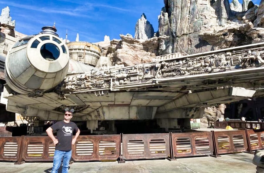 A man posing in front of The Millennium Falcon in Star Wars Land during daytime