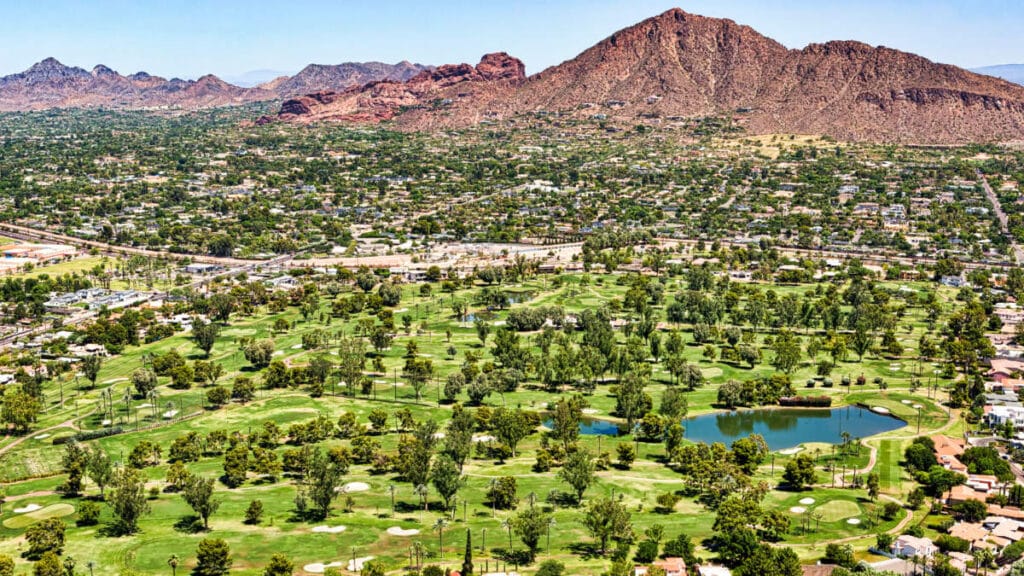Aerial view of a golf course and residential area below Camelback Mountain in Phoenix