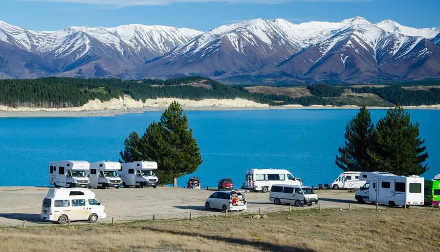 View of campervans with the Lake Pukaki and a snowy mountain on the background