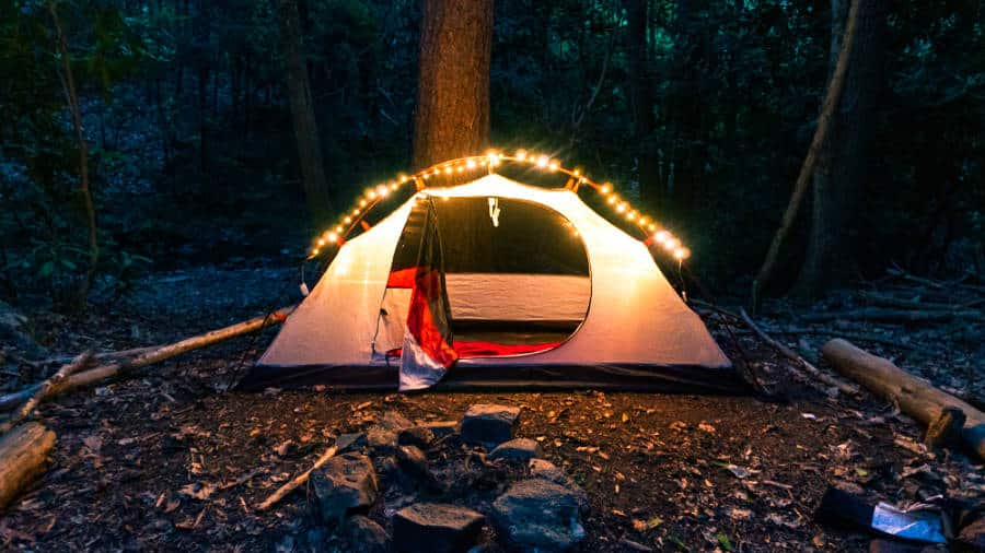 View of a camping tent illuminated with fairy lights in the dark