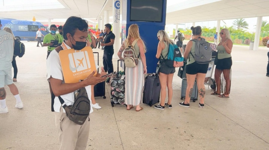 A guide with an orange suitcase sign in the Cancun airport